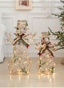 Close-up of twine snowman with red plaid bow, pine needles and warm LED lights