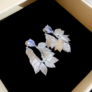 Detailed close-up of silver tassel earrings with zircon studs and hollow leaf pendants