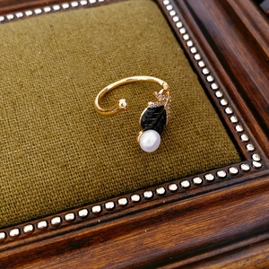 Detail view of a vintage gold-plated ring with pearl and black stone on green velvet