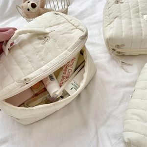 Detailed view of the open quilted makeup bag showing spacious interior with beauty items