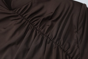 Dettaglio del tessuto arricciato marrone scuro con pieghe eleganti e materiale elasticizzato