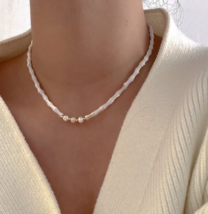 Close-up of minimalist bamboo-style necklace with natural pearls on a female model
