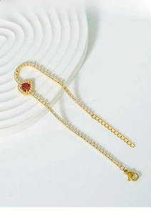 Detail of titanium steel gold necklace with sparkling heart-shaped red gemstone pendant