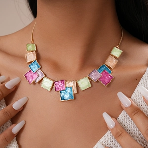 Detail of a gold-tone necklace with colorful geometric enamel squares on a model