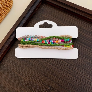Macro detail of multi-layered colorful beaded bracelets on a rustic wood surface