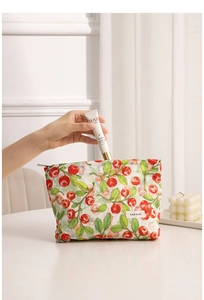 Neceser floral con patrones de bayas rojas mostrando el guardado de cremas y envases