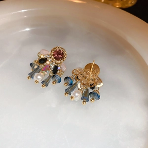 Macro view of gold stud earrings with pink crystal and colorful beaded drop details