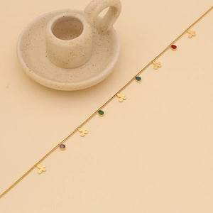 Detail of gold butterfly necklace with colorful teardrop pendants on beige background