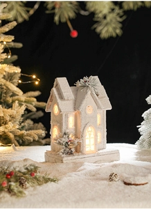 Macro detail of glowing Christmas wooden house with warm LED light and faux snow texture