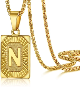 Detailed macro view of gold-plated rectangular pendant necklace featuring raised letter N