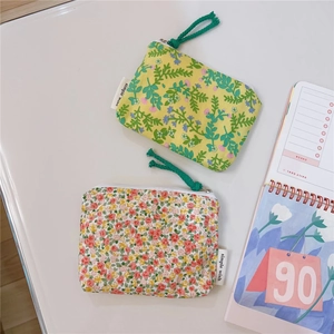 Close-up of floral cotton coin purses with zippers and brand labels on white desk