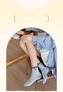 Detail of light blue cotton socks with grey cuffs and small puppy cartoon embroidery