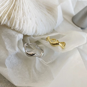 Macro detail of irregular wave lava rings in gold and silver finish with minimalist texture