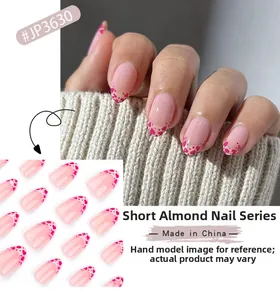 Unghie finte a mandorla corta con base rosa French e motivi a cuore rosso dettagliati