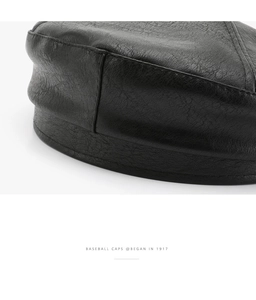 Close-up of black litchi grain faux leather texture on retro octagonal beret cap