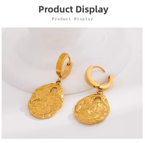Detailed close-up of golden hammered hoop earrings on a minimalist white platform