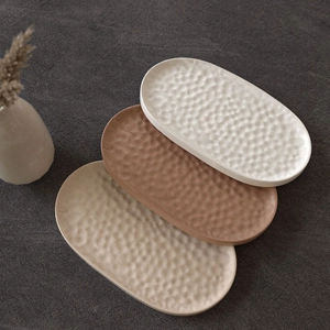 Three-piece oval decorative tray set with handcrafted hammered texture in earthy tones