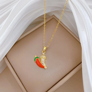 Close-up of a gold chili pepper necklace with red enamel and sparkling crystal pavé stones