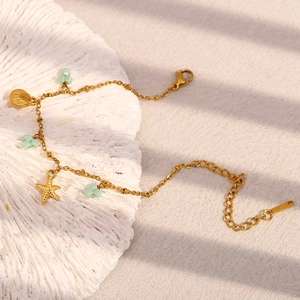 Détails des breloques étoile de mer et coquillage en or 18K sur un bracelet océan