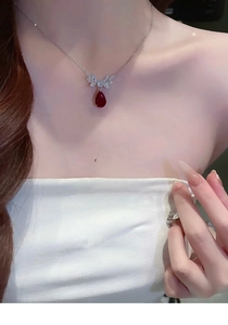 Detail view of silver butterfly necklace with sparkling pave diamonds and red teardrop gem