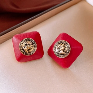 Close-up of red faux leather diamond earrings with vintage gold Alexander coin detail