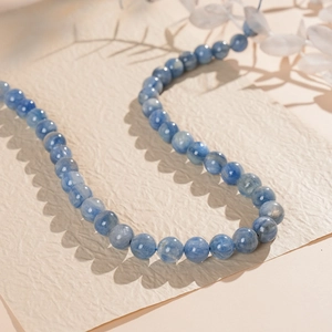 Macro shot of blue kyanite beaded necklace showing natural stone textures on beige paper