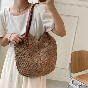 Handwoven straw tote bag with brown leather handles for beach vacation style