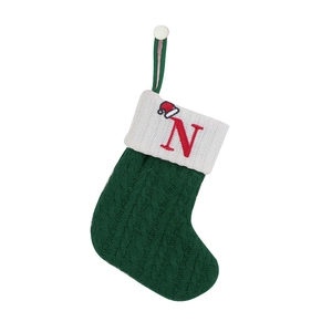 Detail of green knitted Christmas stocking with white cuff and red embroidered letter N