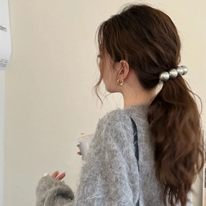 Minimalist silver bead hair tie and gold twisted hoop earrings worn by a model