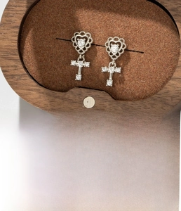 Detailed view of silver heart cross earrings featuring titanium steel and zircons