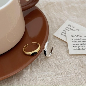 Minimalist 925 sterling silver adjustable rings with black onyx on a coffee cup