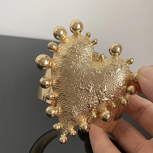Macro view of gold heart cuff bracelet featuring hammered texture and metallic beads