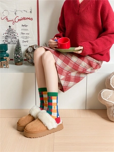Close-up of winter camel suede slippers with plush trim and festive Christmas socks