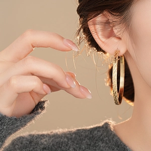 Details von 4cm goldenen geometrischen Creolen mit diagonalem Muster an einem Modell