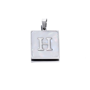 Detail of silver square pendant with white shell inlay and metallic letter H charm