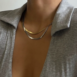 Close-up of gold and silver flat snake chains worn by a model to show texture and shine
