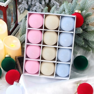 Close-up of pink, beige, and blue flocked Christmas ornaments in a gift box with festive decor