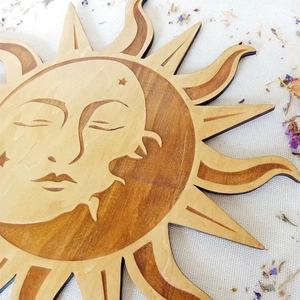 Close-up of sun-shaped wooden wall art featuring intricate facial carving and grain details