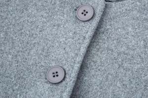 Close-up of grey wool coat showing detailed fabric texture and dark four-hole buttons