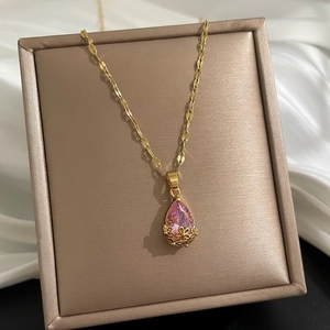 Détail du pendentif en cristal rose en forme de poire avec motifs dorés sur soie