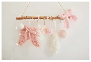 Detail of knit and plush Christmas ornaments hanging on a natural wooden branch