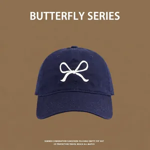 Close-up of fine white bow embroidery on navy blue cotton sun hat with clean texture