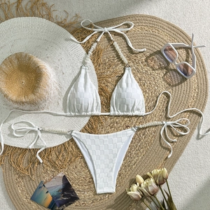Close-up of white checkerboard textured bikini with elegant pearl accents on a woven mat