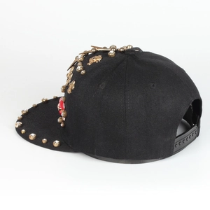 Detail of hiphop snapback with gold studs, cross motifs and red gemstones on black cotton