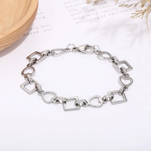 Macro shot of stainless steel bracelet with square and hollow heart links on a wood tray