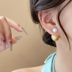 Detail view of retro french double-sided pearl and matte gold ball earrings on ear