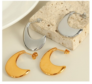 Detail view of gold and silver teardrop earrings on a natural stone base