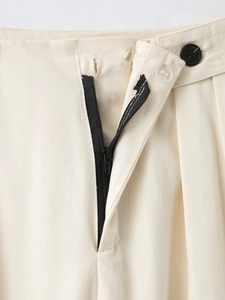 Détail du pantalon taille haute abricot en tissu sergé avec fermeture boutonnée et éclair