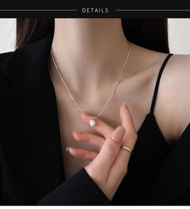 Detail view of a freshwater baroque pearl pendant on a silver stainless steel chain necklace