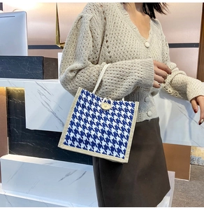 Detail of woven houndstooth handbag featuring a wooden button closure and rope handle